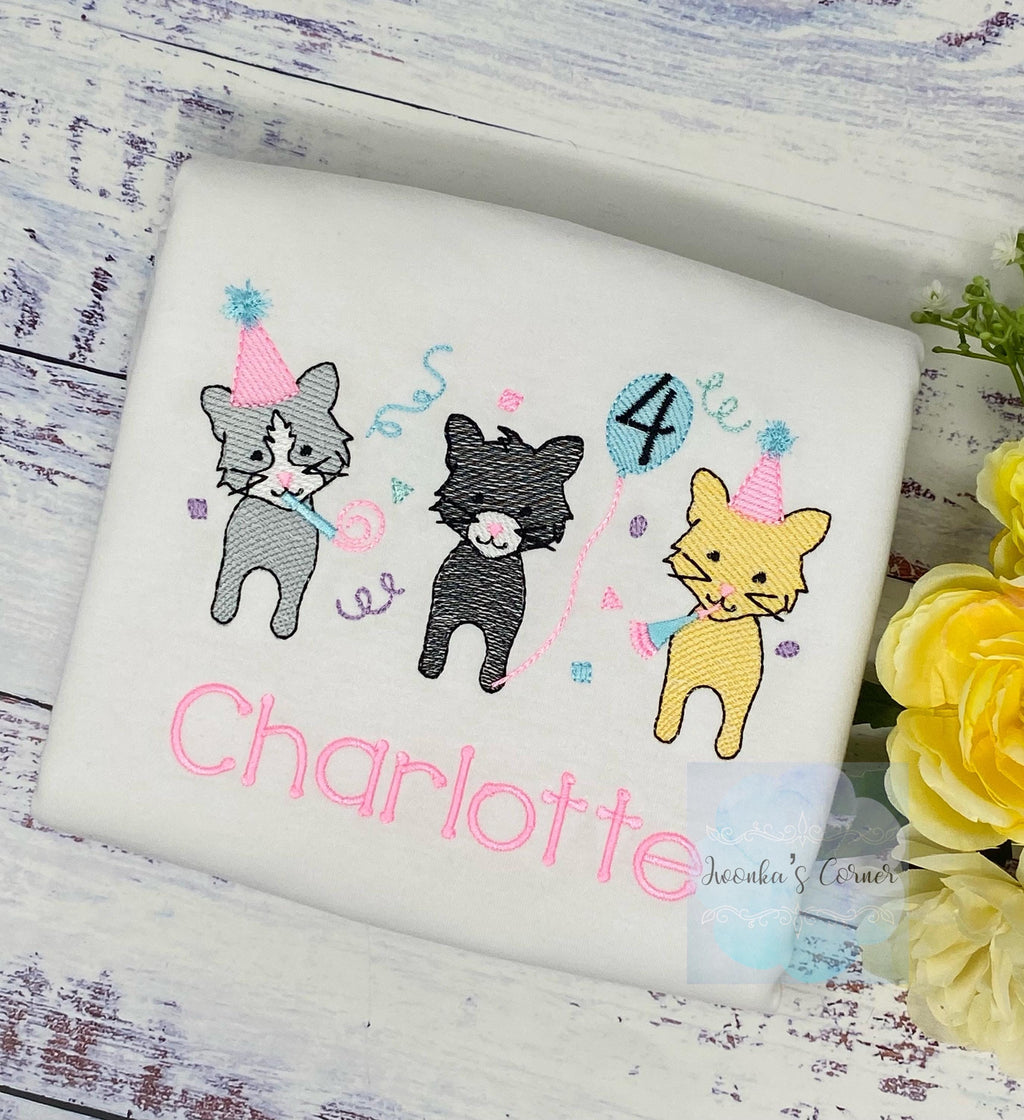 May include: White t-shirt featuring three cartoon cats celebrating a birthday. The cats are in gray, black, and yellow, wearing party hats and holding noisemakers and a balloon with the number 4. The name is embroidered in pink.